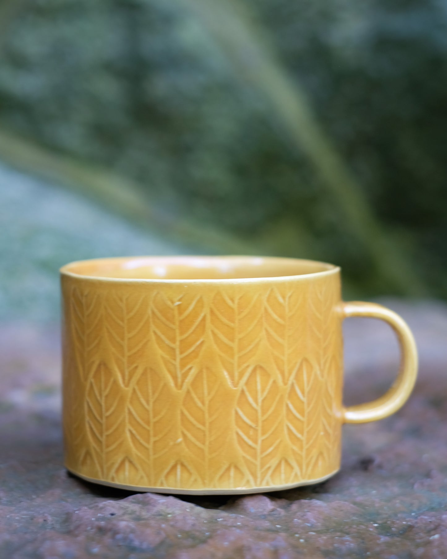 Kavlad kopp med lövmönster senapsgul